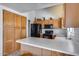 Well-lit kitchen with light wooden cabinets, black appliances, and white countertops offer ample workspace at 17317 N Ponca Way, Surprise, AZ 85374