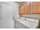 Spacious laundry room featuring washer and dryer with oak cabinets above at 17317 N Ponca Way, Surprise, AZ 85374