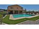 A backyard featuring a refreshing pool, well-manicured artificial turf, and a covered balcony at 1932 S 220Th Dr, Buckeye, AZ 85326