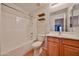 Well-lit bathroom featuring a shower-tub combo, vanity with wooden cabinets, and accent shelves at 1932 S 220Th Dr, Buckeye, AZ 85326