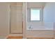Bathroom featuring separate tub and shower with neutral tile floor and a window for natural light at 1932 S 220Th Dr, Buckeye, AZ 85326