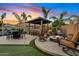 Expansive backyard with an outdoor kitchen, fire pit, lounge chairs and desert sunset views at 19748 E Walnut Rd, Queen Creek, AZ 85142