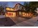 Two-story home showcasing a garage with stone accents and a balcony, beautifully lit up at dusk at 20689 W Valley View Dr, Buckeye, AZ 85396