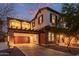 Two-story home with stone accents and a balcony above the garage, beautifully illuminated at twilight at 20689 W Valley View Dr, Buckeye, AZ 85396