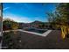 Beautiful backyard with a pool, lush landscaping, and ambient lighting creating a serene outdoor space at 21194 W Hillcrest Blvd, Buckeye, AZ 85396