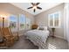 Cozy bedroom featuring wood-look tile floor, ceiling fan, rocking chair, and plenty of natural light at 21194 W Hillcrest Blvd, Buckeye, AZ 85396
