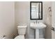 Half bath with pedestal sink, modern faucet, toilet, framed mirror and light gray walls at 21228 N 58Th St, Phoenix, AZ 85054