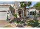 Elegant home exterior featuring a lush garden, mature palm trees, and a circular driveway at 2135 E Clipper Ln, Gilbert, AZ 85234