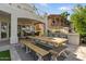 Wide shot of an open patio with a large wooden picnic table, an outdoor bar, and manicured landscape at 2135 E Clipper Ln, Gilbert, AZ 85234