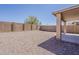 Spacious gravel backyard with a block wall for privacy and a covered patio area at 22328 W Woodlands Ave, Buckeye, AZ 85326