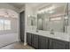 Bathroom featuring a double sink vanity with gray cabinets and a view to bedroom at 22328 W Woodlands Ave, Buckeye, AZ 85326