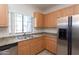 Well-lit kitchen featuring stainless steel appliances, a double sink, and plenty of wood cabinetry at 295 N Rural Rd # 143, Chandler, AZ 85226