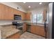 Well-lit kitchen featuring stainless steel appliances, wooden cabinets, and a granite-style countertop at 295 N Rural Rd # 143, Chandler, AZ 85226