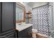 Updated bathroom with a wood mirror, floating wood shelves, and decorative shower curtain at 4415 S Poplar St, Tempe, AZ 85282