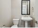 Powder room featuring a pedestal sink, toilet, and a square mirror at 5815 E Covey Ln, Phoenix, AZ 85054