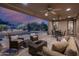 Inviting covered patio with comfortable seating, ceiling fans, and a view of the pool and desert landscape at 6481 E Amber Sun Dr, Scottsdale, AZ 85266