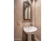 Charming powder room with a pedestal sink, decorative mirror, and textured walls for a touch of elegance at 6481 E Amber Sun Dr, Scottsdale, AZ 85266