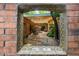 Charming courtyard view through a tile-framed window, with brick walls, pergola, and string lights at 8219 S Pecan Grove Cir, Tempe, AZ 85284