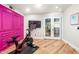 Home gym featuring Peloton bike, hardwood floors, french doors and a vibrant accent wall at 8219 S Pecan Grove Cir, Tempe, AZ 85284