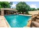 Beautiful backyard pool featuring a rock waterfall and a covered patio with a basketball hoop at 8219 S Pecan Grove Cir, Tempe, AZ 85284
