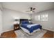 Cozy bedroom with a ceiling fan, a large window with shutters and warm wood floors at 9039 N Concho Ln, Phoenix, AZ 85028