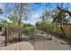 Serene backyard featuring mature trees, desert landscaping, and a decorative iron gate, providing privacy and tranquility at 13019 N 23Rd Pl, Phoenix, AZ 85022