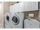 Bright laundry room features white cabinets, a utility sink, and a modern washer and dryer at 157 W Leatherwood Ave, San Tan Valley, AZ 85140