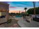 Backyard view of the pool, outdoor kitchen, patio, and desert landscaping during dusk with a sunset at 16608 S 16Th Ave, Phoenix, AZ 85045