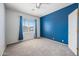 Empty bedroom with light-blue accent wall, ceiling fan, and a window with neighborhood views at 16608 S 16Th Ave, Phoenix, AZ 85045