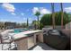 Outdoor kitchen and bar with grill, refrigerator, and cozy seating, overlooking the refreshing pool at 16608 S 16Th Ave, Phoenix, AZ 85045