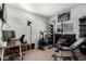 Bright home gym with dark stained desk, weight rack, pull up bar, and various equipment at 1702 W Amberwood Dr, Phoenix, AZ 85045