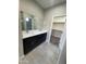 Bathroom featuring double sinks, dark cabinetry, gray walls and floors, and a walk-in closet at 1835 E Burgess Ln, Phoenix, AZ 85042