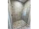 Modern walk-in shower with stylish gray tile walls, pebble floor, and a frameless glass enclosure at 1835 E Burgess Ln, Phoenix, AZ 85042
