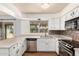Updated kitchen featuring stainless steel appliances, ample counter space, white cabinets, wood-look flooring and backyard view at 2215 W Straford Dr, Chandler, AZ 85224
