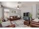 Inviting living room with plush leather furniture, a large rug, ceiling fan, and a decorative shelf with picture frames at 3480 E Cullumber Ct, Gilbert, AZ 85234