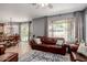 Open-concept living room with a tan tile floor, access to the backyard, a brown leather sofa, and a ceiling fan at 3480 E Cullumber Ct, Gilbert, AZ 85234