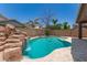 Beautiful backyard pool with rock waterfall feature, set against a backdrop of mature trees and neighborhood houses at 3480 E Cullumber Ct, Gilbert, AZ 85234