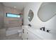 Modern bathroom features a double sink vanity, unique mirrors, and a neutral tiled shower with window at 3831 N 8Th St, Phoenix, AZ 85014