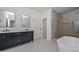 Modern bathroom featuring a double vanity with black cabinets, soaking tub, and luxurious marble-clad shower at 3831 N 8Th St, Phoenix, AZ 85014