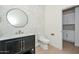 Stylish powder room featuring a modern black vanity, marble countertop, round mirror, and adjacent room with white cabinets at 3831 N 8Th St, Phoenix, AZ 85014