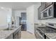 Close-up of a kitchen featuring stainless steel appliances, granite counters, and dark wood cabinets at 40060 W Wade Dr, Maricopa, AZ 85138