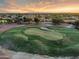 An aerial view of a green golf course and sand bunker, nestled in a community with a beautiful desert sunset at 4906 S Verbena Ave, Gilbert, AZ 85298