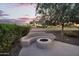 Landscaped backyard featuring a concrete firepit, cozy seating area, mature tree, and desert landscaping at 4906 S Verbena Ave, Gilbert, AZ 85298