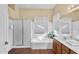 Bright bathroom with a walk-in shower, soaking tub, dual sinks, and decorative wallpaper at 4906 S Verbena Ave, Gilbert, AZ 85298