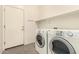 Bright laundry room equipped with a front-load washer and dryer, tiled floors, and white door at 689 E Stottler Dr, Gilbert, AZ 85296