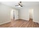 Bright bedroom featuring neutral walls, wood-look flooring, and an open doorway to another room at 7503 W Julie Dr, Glendale, AZ 85308
