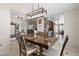 Open dining room with a rustic table, modern lighting, and a view of the adjacent kitchen and living spaces at 7503 W Julie Dr, Glendale, AZ 85308