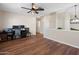 Open-concept living space with wood floors, neutral walls, and a ceiling fan above an office workspace at 7503 W Julie Dr, Glendale, AZ 85308