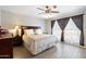 Comfortable main bedroom with wood flooring, ceiling fan, and a large window with privacy curtains at 7503 W Julie Dr, Glendale, AZ 85308