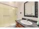 Close up of bathroom featuring tile floors, enclosed shower with sliding glass doors and a black framed mirror at 7722 W Libby St, Glendale, AZ 85308
